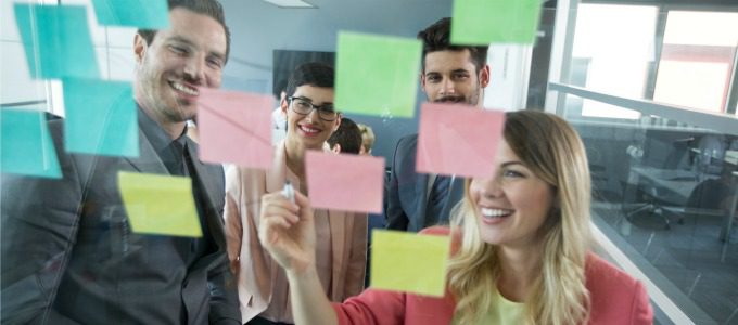 Smiling modern partners looking at sticky notes
