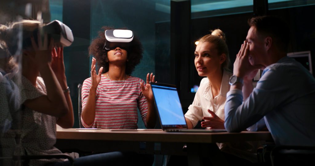 Multiethnic Business team using virtual reality headset in night office meeting Developers meeting with virtual reality simulator around table in creative office.